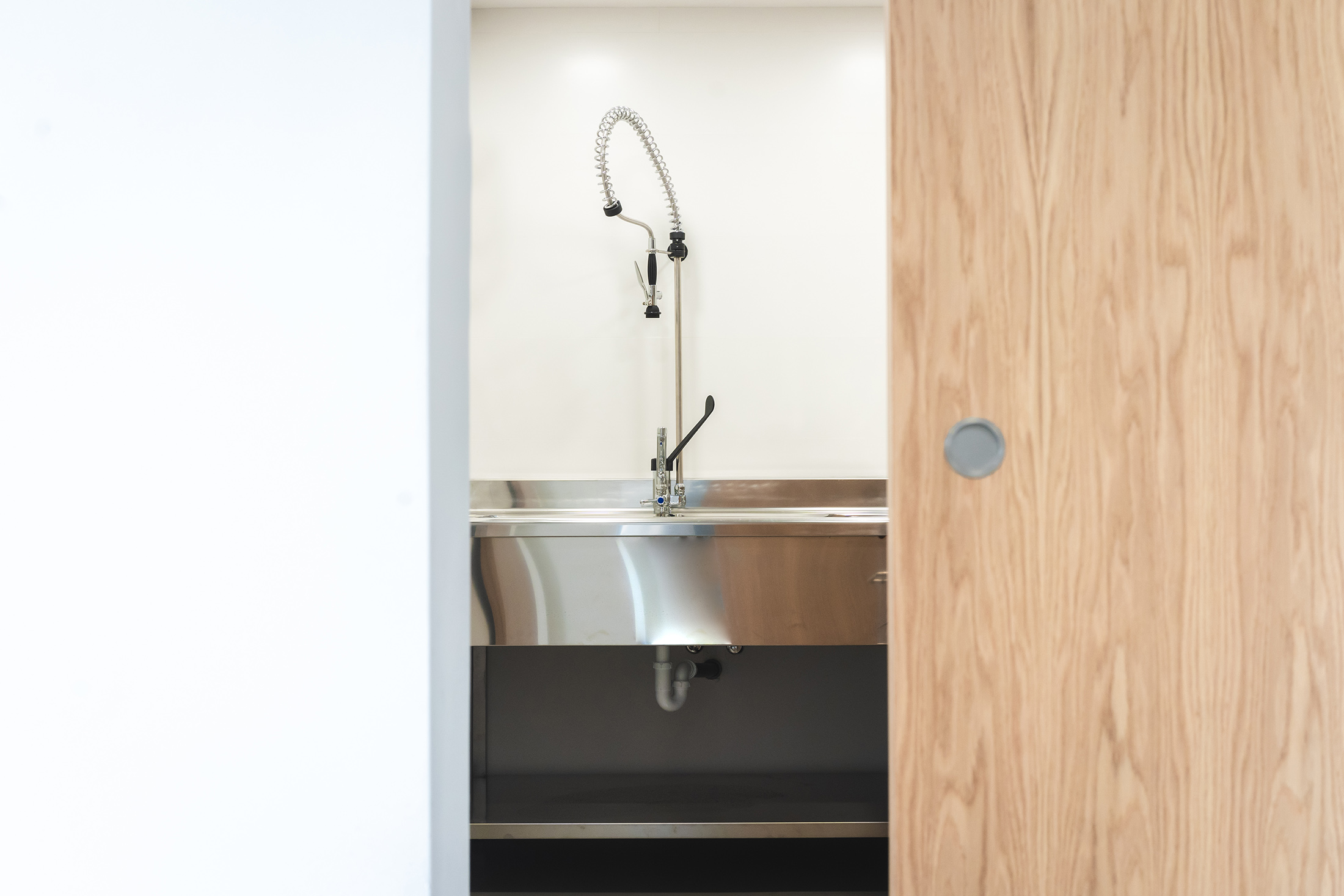 Detalle de lavabo de acero inoxidable integrado en mobiliario de madera